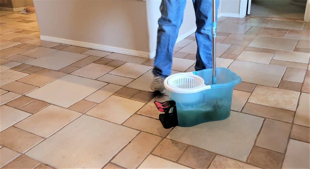 Professional tile and grout cleaning in a residential home using a mop and bucket for deep floor maintenance